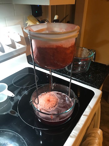 Jelly bag drips juices on top of a stove. 
